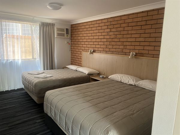 A twin room with two beds, a brick feature wall and bedside lamps